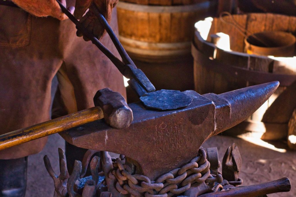 Close-up of a blacksmith hammering iron on an anvil in a traditional workshop.