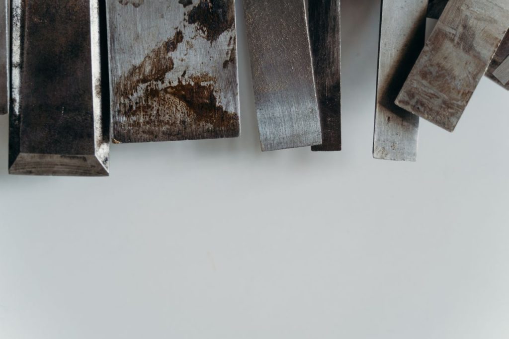 An abstract still life of textured metal pieces on a white surface.